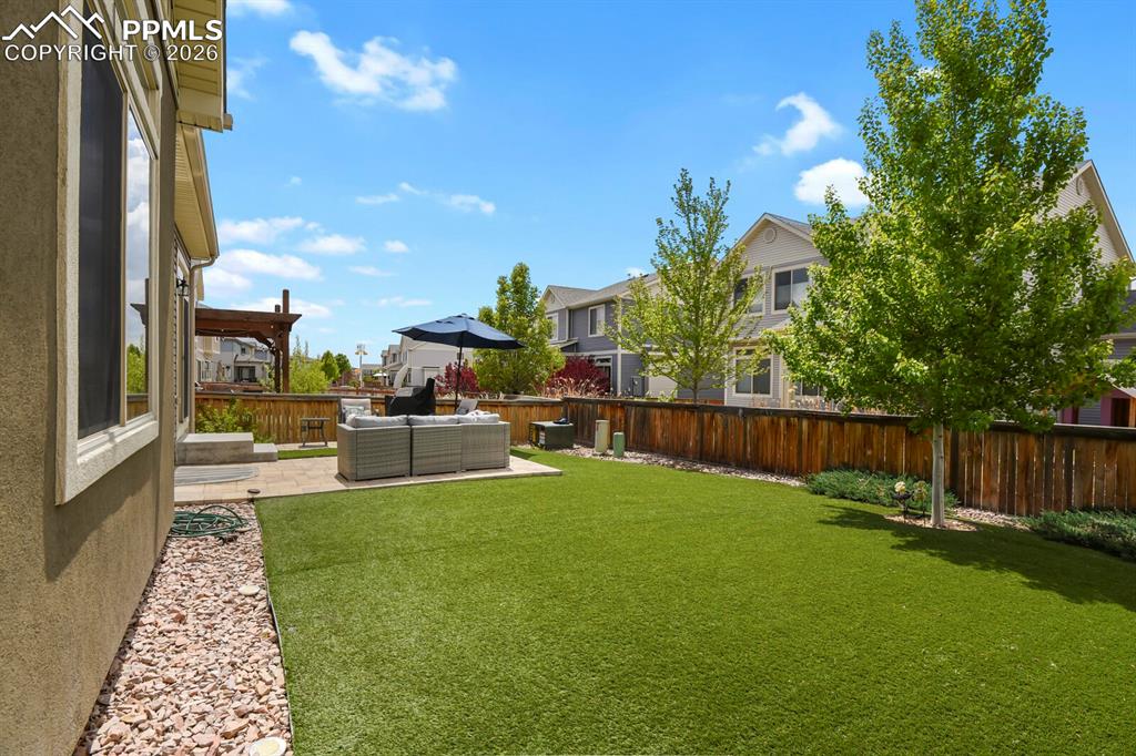 Image 36 of 39: Expansive backyard featuring a paver patio and artificial turf offering low