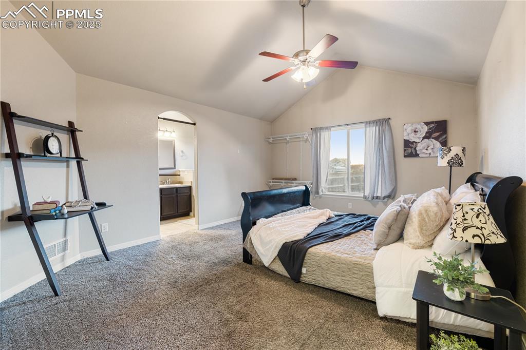 Image 17 of 46: Bedroom with ceiling fan, connected bathroom, vaulted ceiling, and light ca