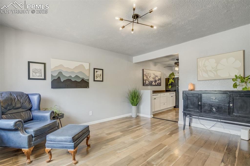 Image 2 of 24: Sitting room featuring light wood-style floors, a chandelier, a ceiling fan