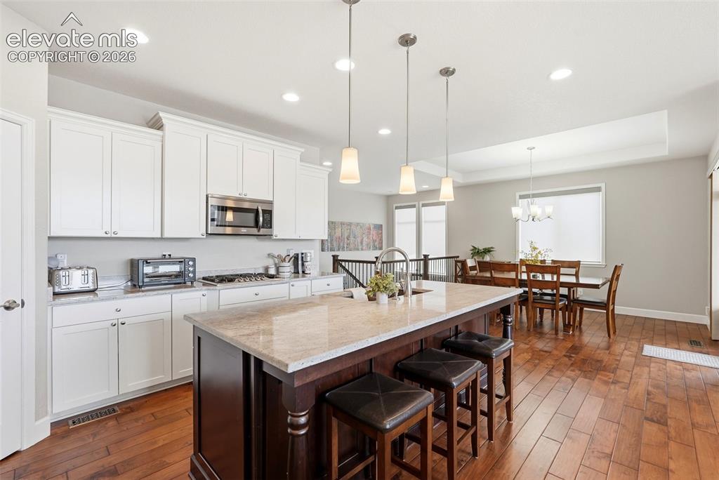 Image 11 of 47: Kitchen featuring a large central island with seating, white shaker-style c