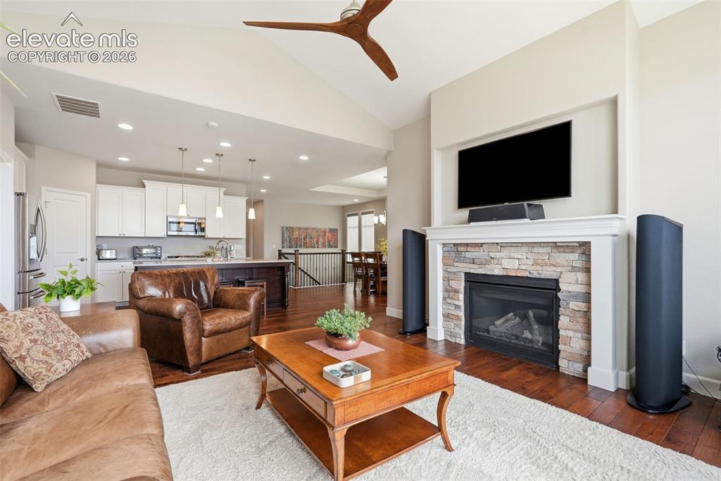 Image 17 of 47: Living area featuring a stone-faced fireplace with a white mantel, wood-fin