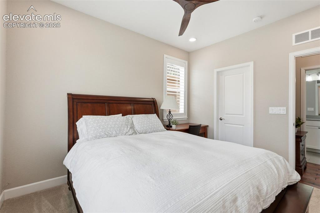 Image 23 of 47: Bedroom featuring a wood-finish bed frame, carpet flooring, and a contempor