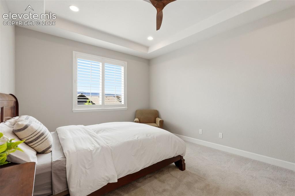 Image 24 of 47: Bedroom featuring a tray ceiling with recessed lighting, a ceiling fan, and