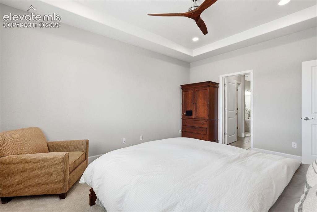 Image 26 of 47: Recessed lighting, ceiling fan with wood-finish blades, and tray ceiling de