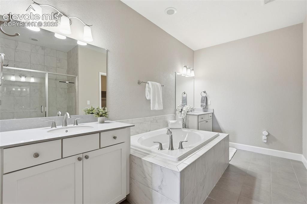 Image 27 of 47: Spacious bathroom featuring a built-in soaking tub with marble-look surroun