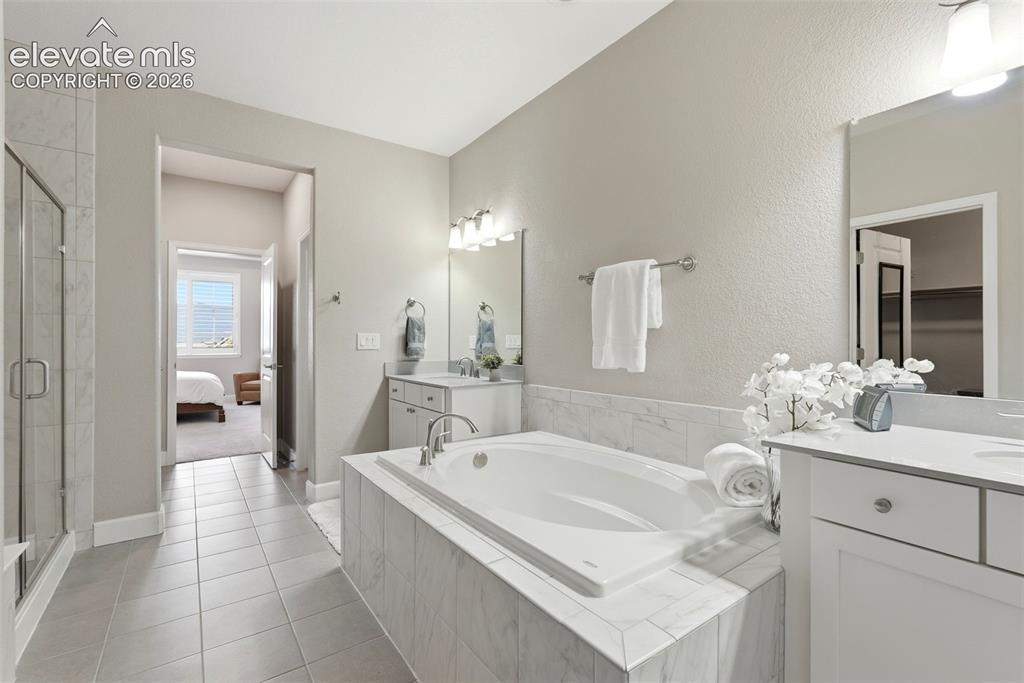 Image 28 of 47: Full bathroom featuring a built-in soaking tub with a tiled surround, a sep