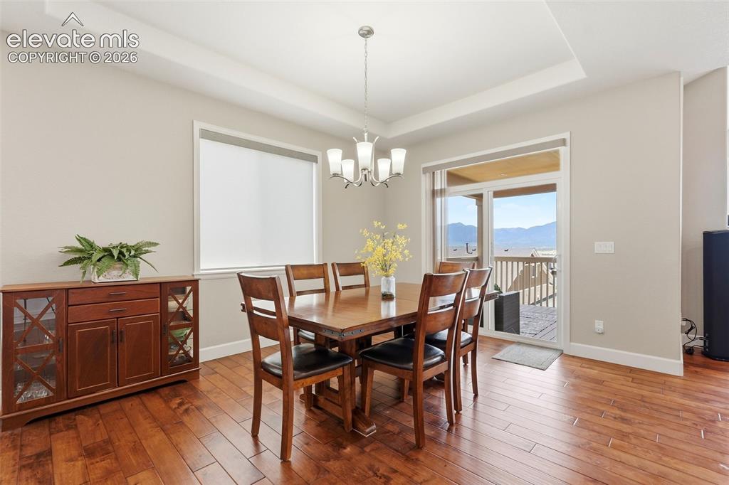 Image 3 of 47: Dining area featuring wood-finish flooring, a tray ceiling with a chandelie