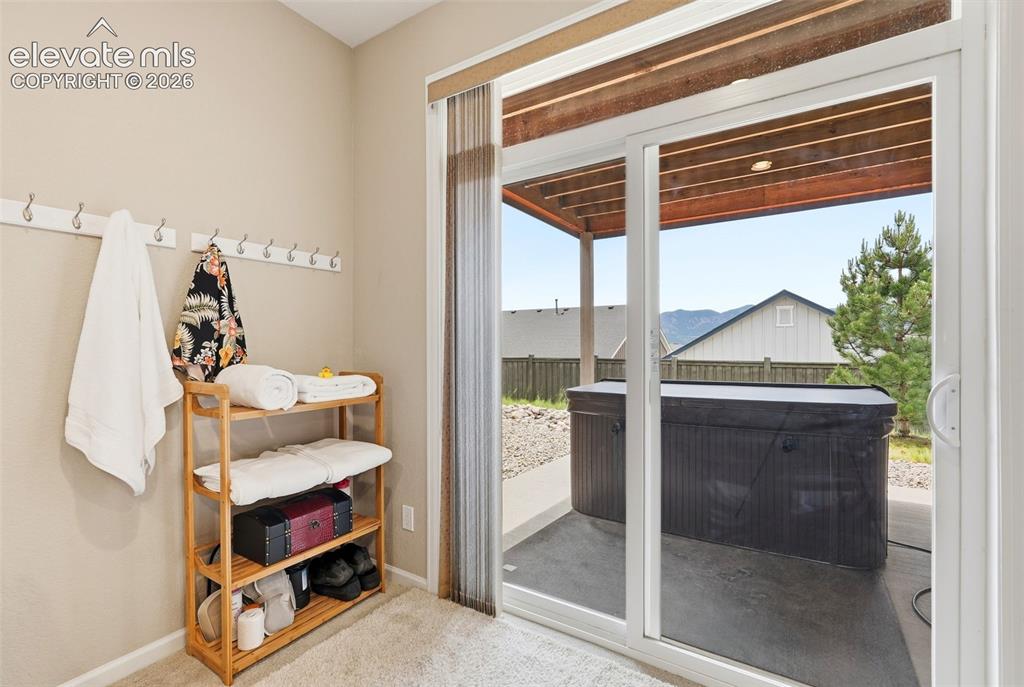 Image 32 of 47: Sliding glass door opening to an outdoor patio area with a covered hot tub