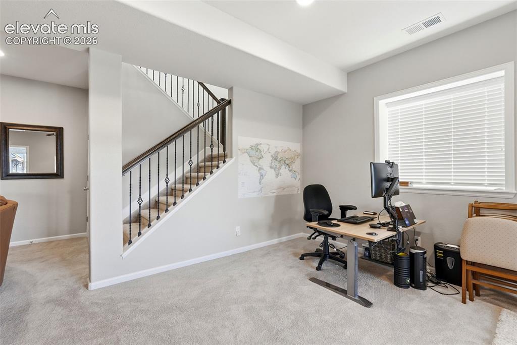 Image 34 of 47: Carpeted interior space featuring a staircase with wrought iron balusters a
