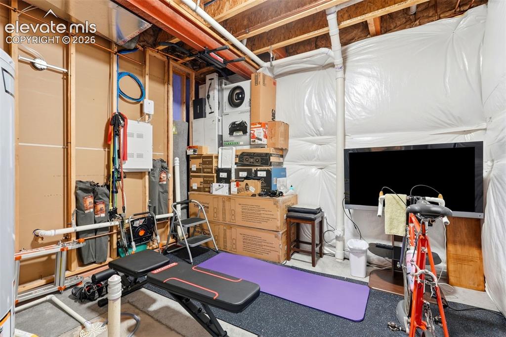 Image 37 of 47: Unfinished basement space with exposed wooden joists, utility piping, and a