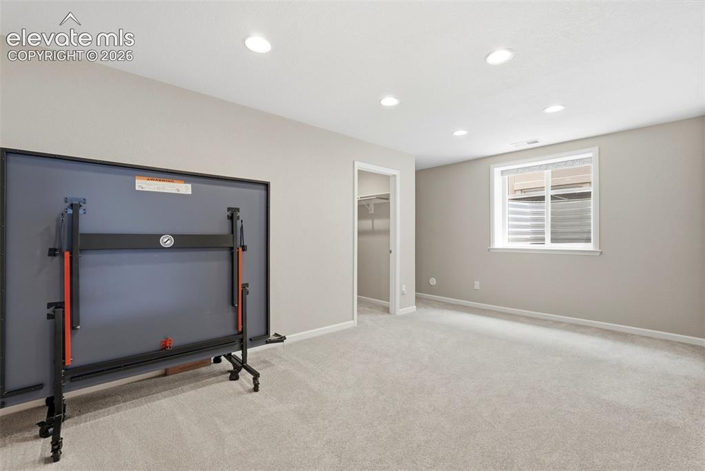 Image 38 of 47: Carpeted room featuring recessed lighting, a white-framed window, and a bui