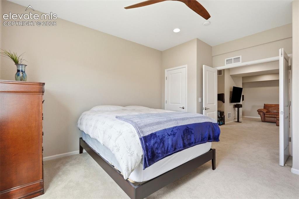 Image 43 of 47: Carpeted sleeping area featuring a ceiling fan, recessed lighting, and a ne