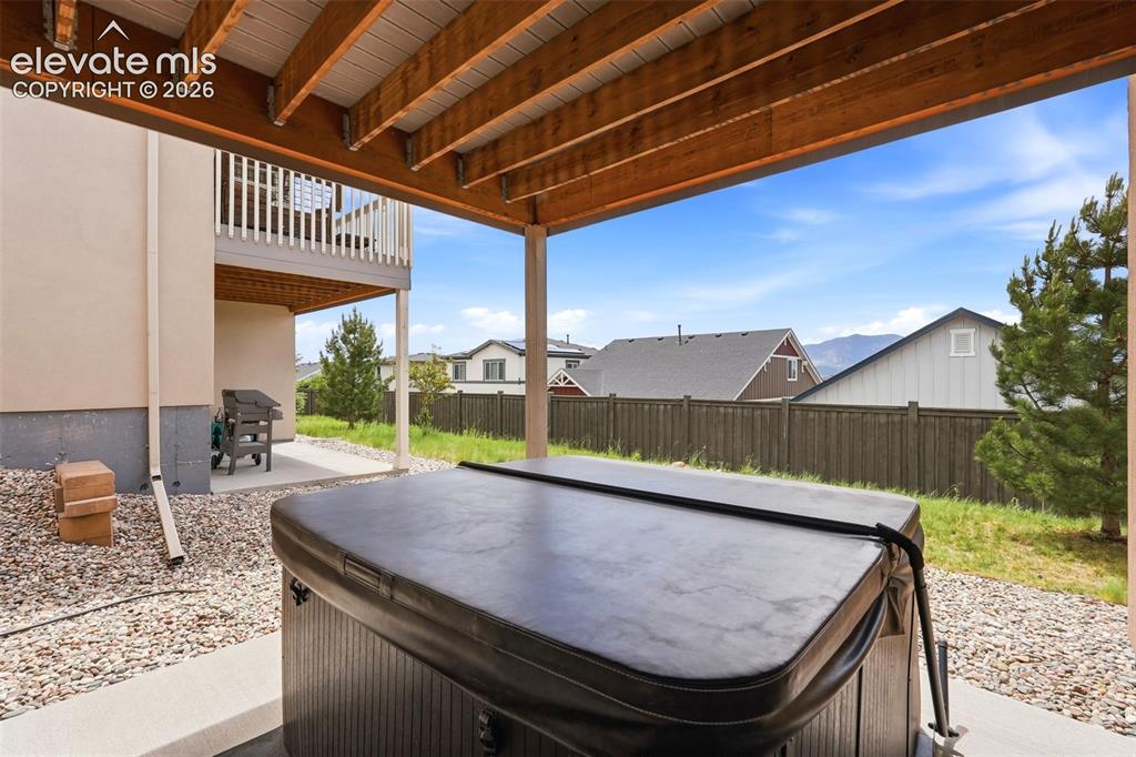 Image 47 of 47: Covered patio area featuring a hot tub, concrete pad, and gravel surround