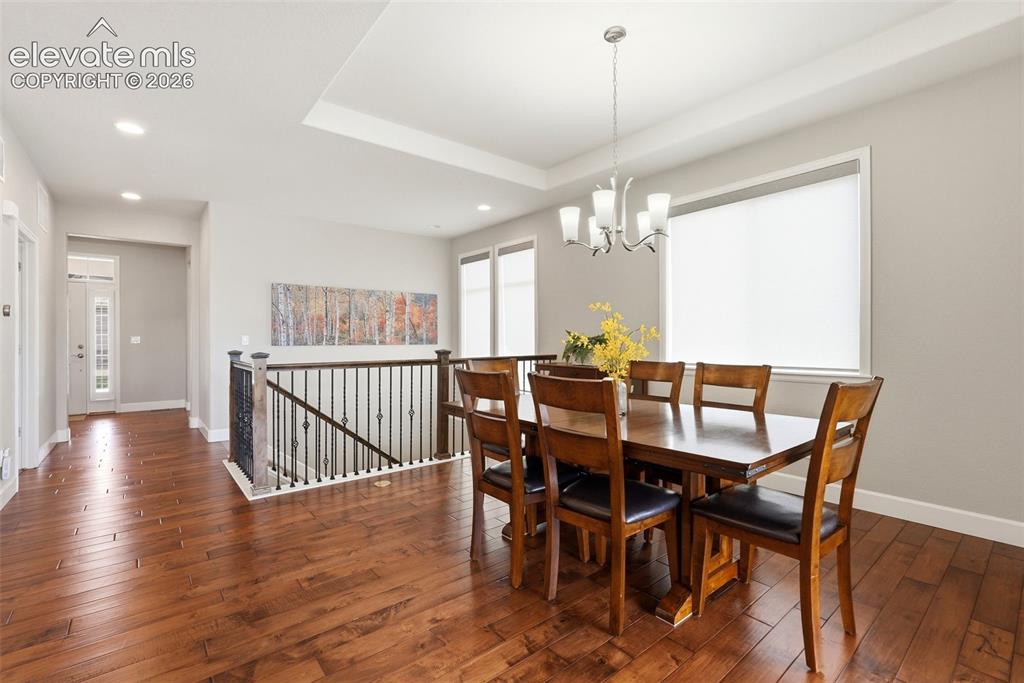 Image 5 of 47: Dining area featuring wood-finish flooring, a tray ceiling with recessed li