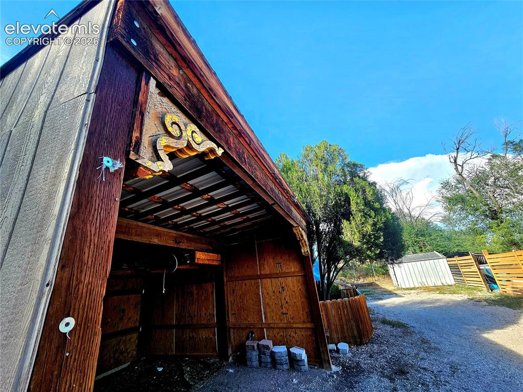 Image 32 of 39: Partially enclosed carport with corbels