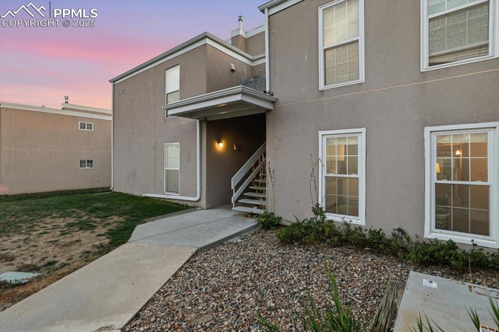 Image 20 of 25: Entrance to property with stucco siding, a chimney, and a lawn