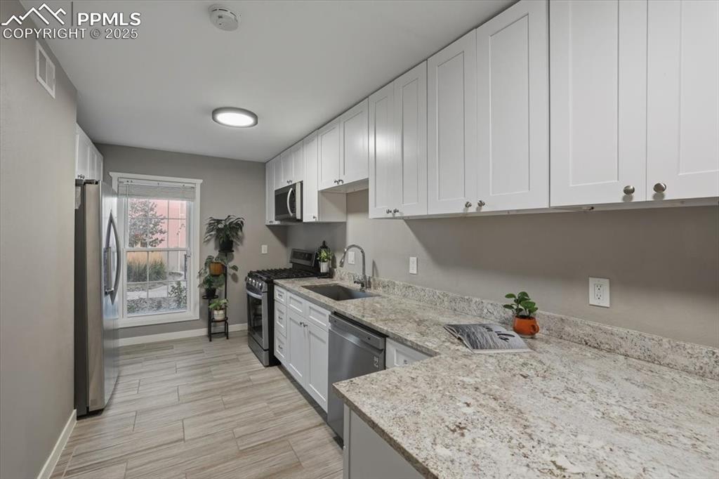 Image 3 of 25: Kitchen featuring appliances with stainless steel finishes, white cabinets,