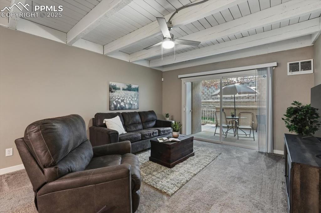 Image 7 of 25: Living area featuring beamed ceiling, light carpet, and ceiling fan