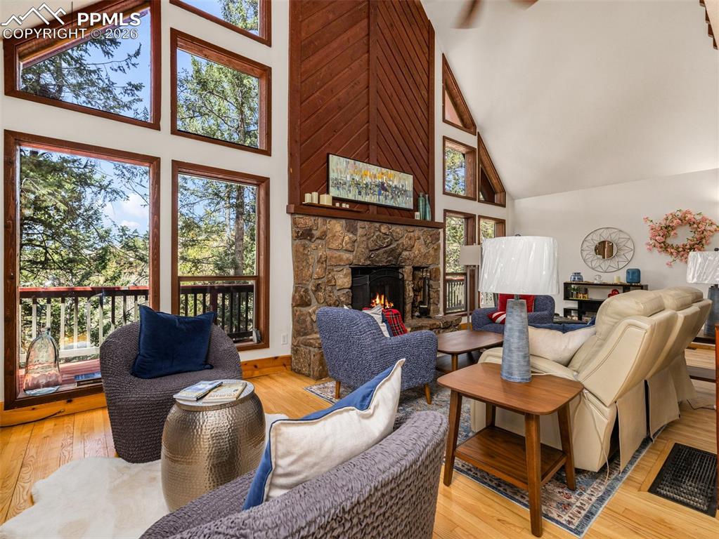 Image 10 of 38: Living room featuring light wood-style floors, vaulted ceiling, and a firep