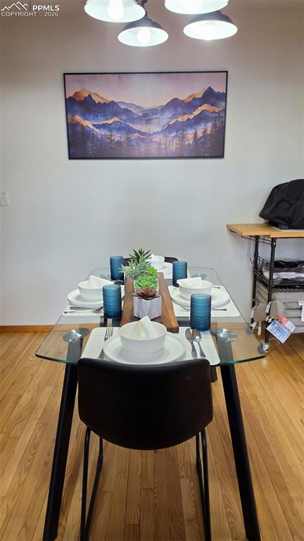 Image 12 of 38: Dining area featuring wood-finish flooring, a glass-top table with black le
