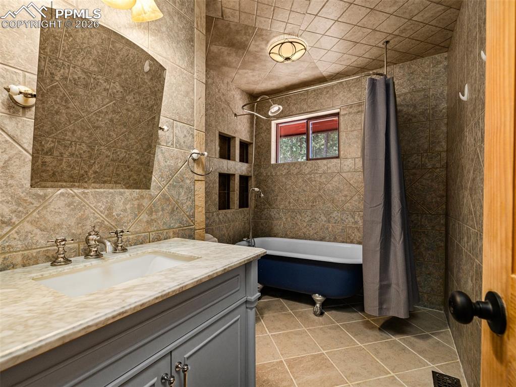 Image 15 of 37: Full bathroom with vanity, tile walls, shower / bathtub combination with cu