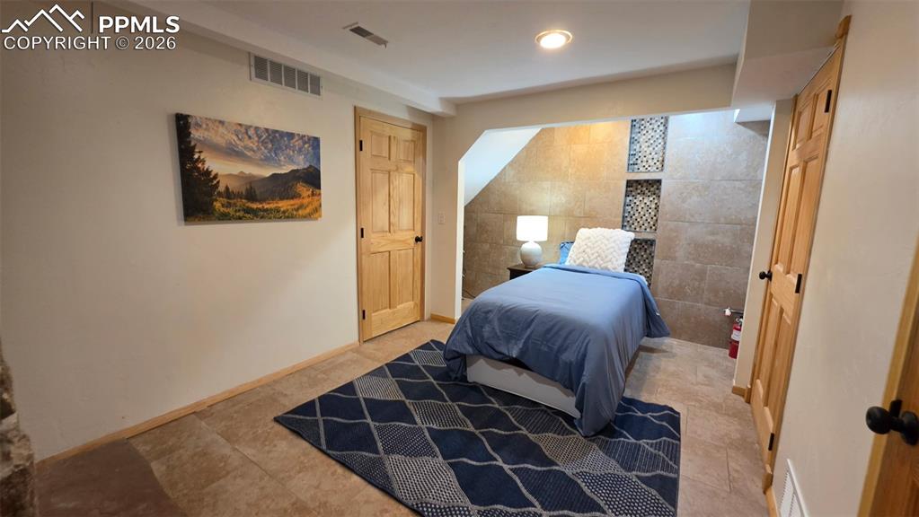 Image 20 of 38: Bedroom with neutral wall paint and wood-finish doors
