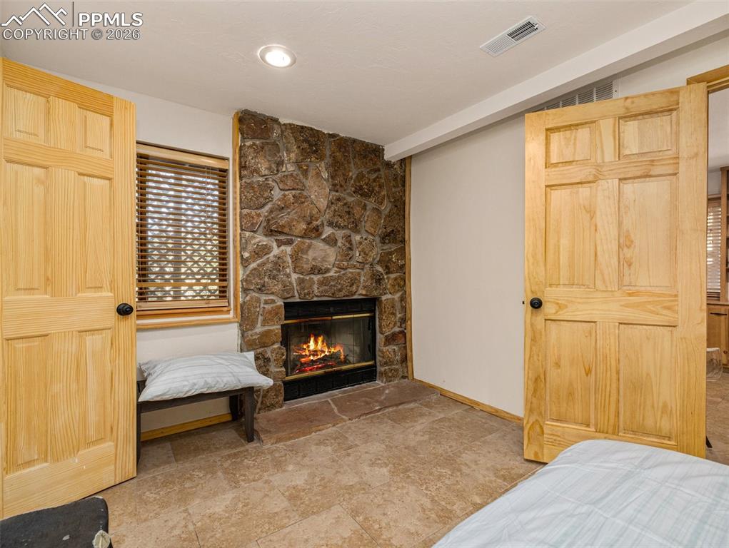 Image 21 of 38: Bedroom with a stone fireplace and vaulted ceiling
