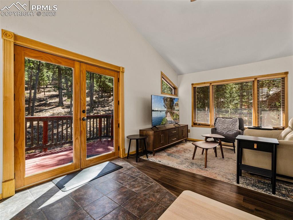 Image 27 of 38: Living room featuring lofted ceiling, plenty of natural light, and dark woo