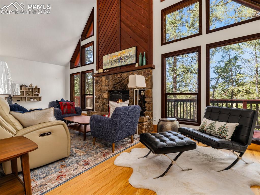 Image 7 of 38: Living area featuring hardwood / wood-style flooring, a stone fireplace, an