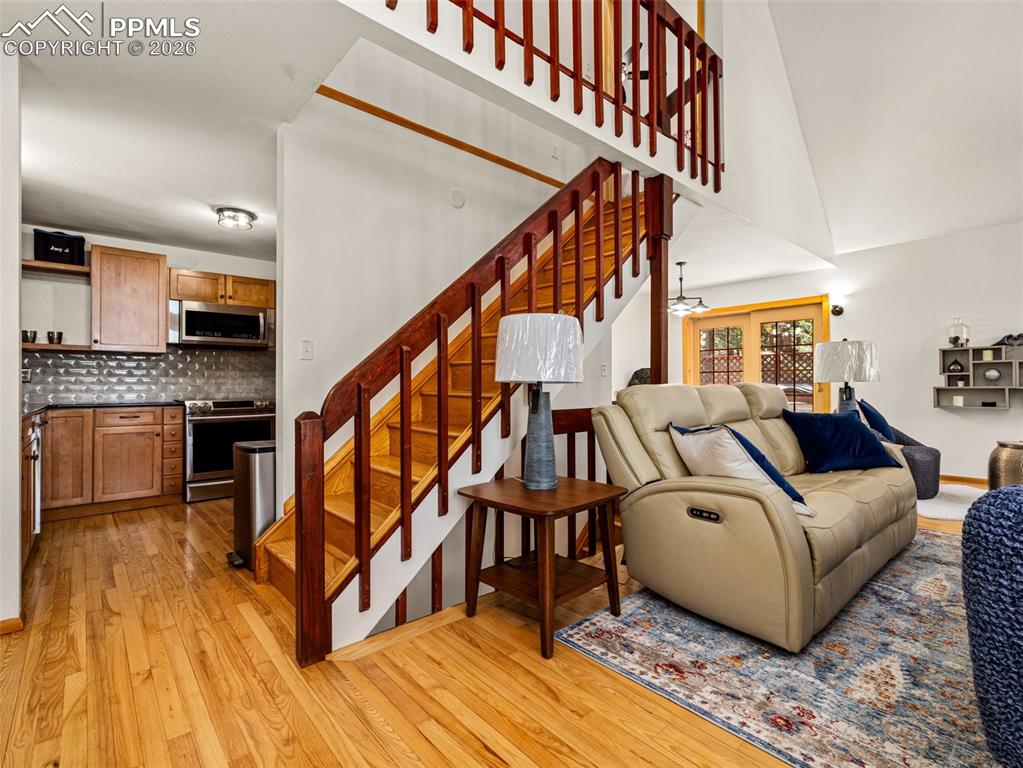 Image 8 of 38: Living area with light wood-style flooring, ceiling fan, and vaulted ceilin