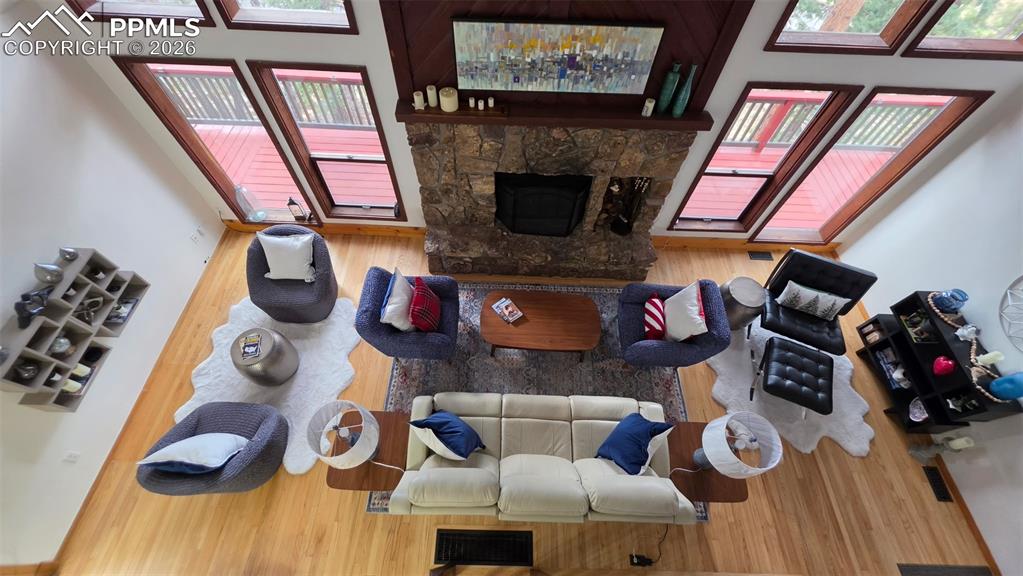 Image 9 of 38: Vaulted ceiling living area featuring wood-finish flooring, a stone-clad fi