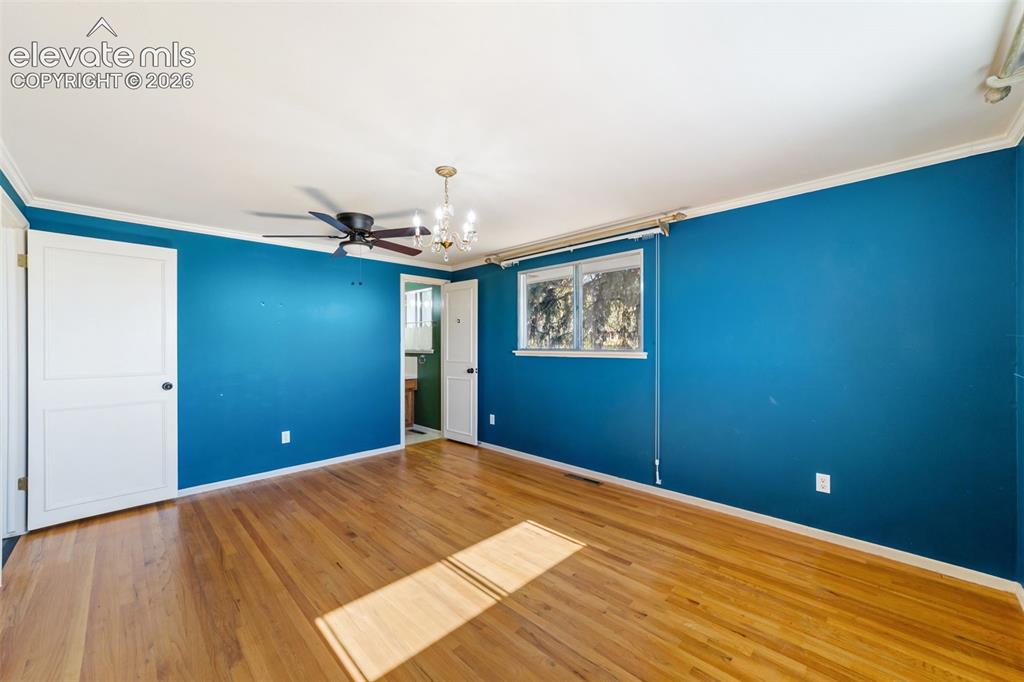 Image 16 of 50: Spacious room featuring wood-finish flooring, a ceiling fan, and a chandeli