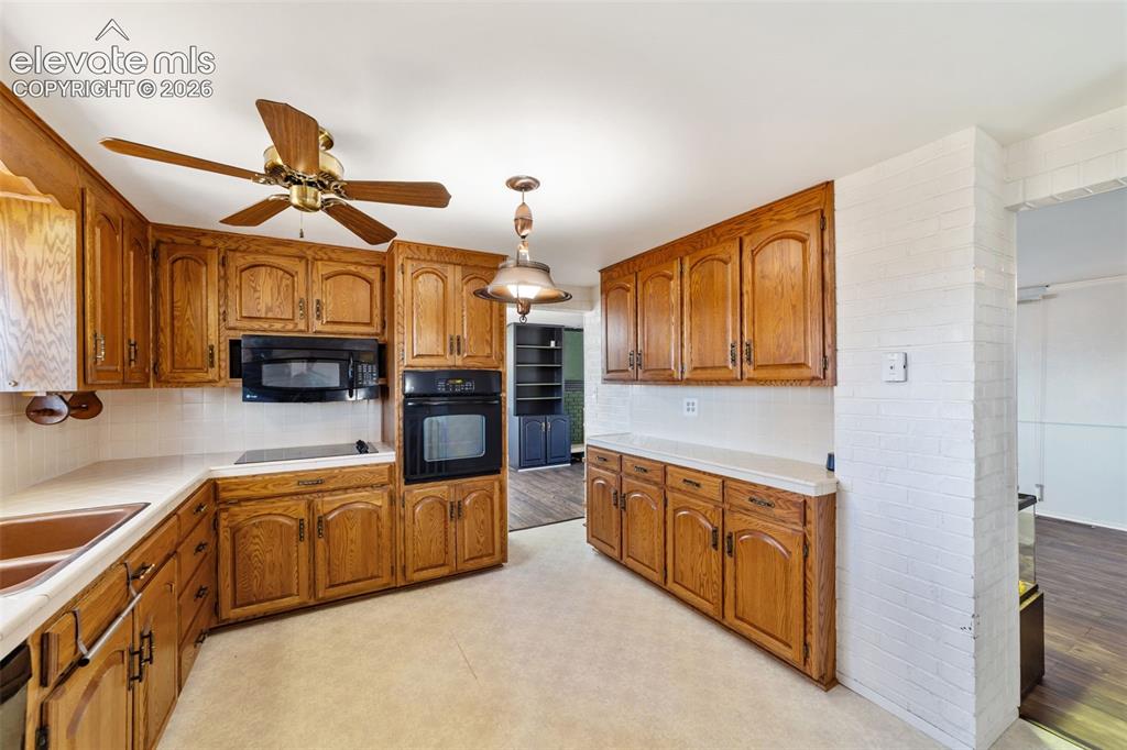 Image 2 of 50: Kitchen featuring extensive wood-finish cabinetry, light-toned countertops,