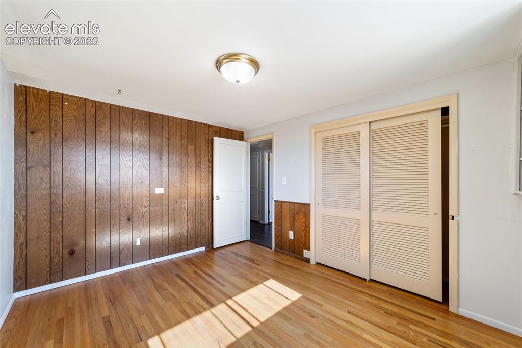 Image 22 of 50: Room featuring wood-finish flooring, a wood-paneled accent wall, neutral wa