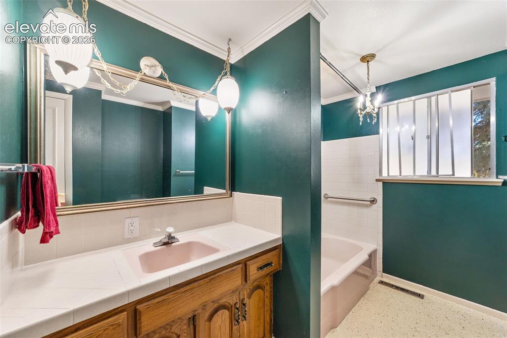 Image 25 of 50: Bathroom vanity featuring a tile countertop with a pink drop-in sink, wood-