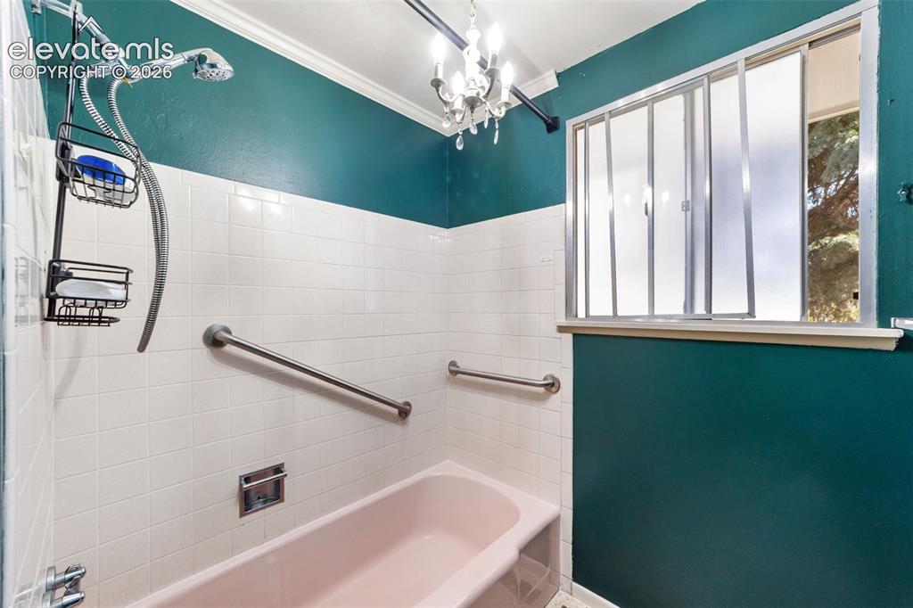 Image 26 of 50: Bathroom featuring a pink bathtub, white tiled walls, and teal painted wall