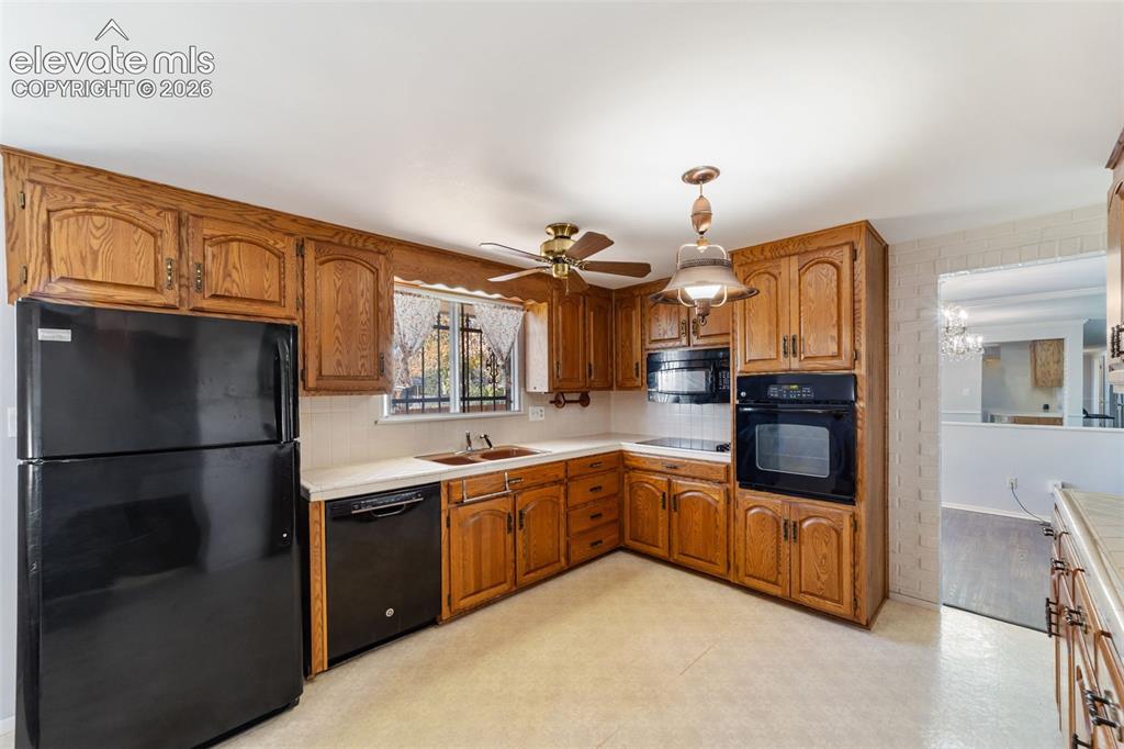 Image 3 of 50: Kitchen featuring wood cabinetry, black appliances including a refrigerator