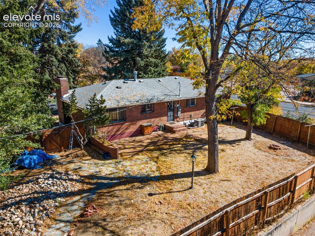 Image 40 of 50: Brick exterior residence featuring a gray shingled roof, a chimney, and mat