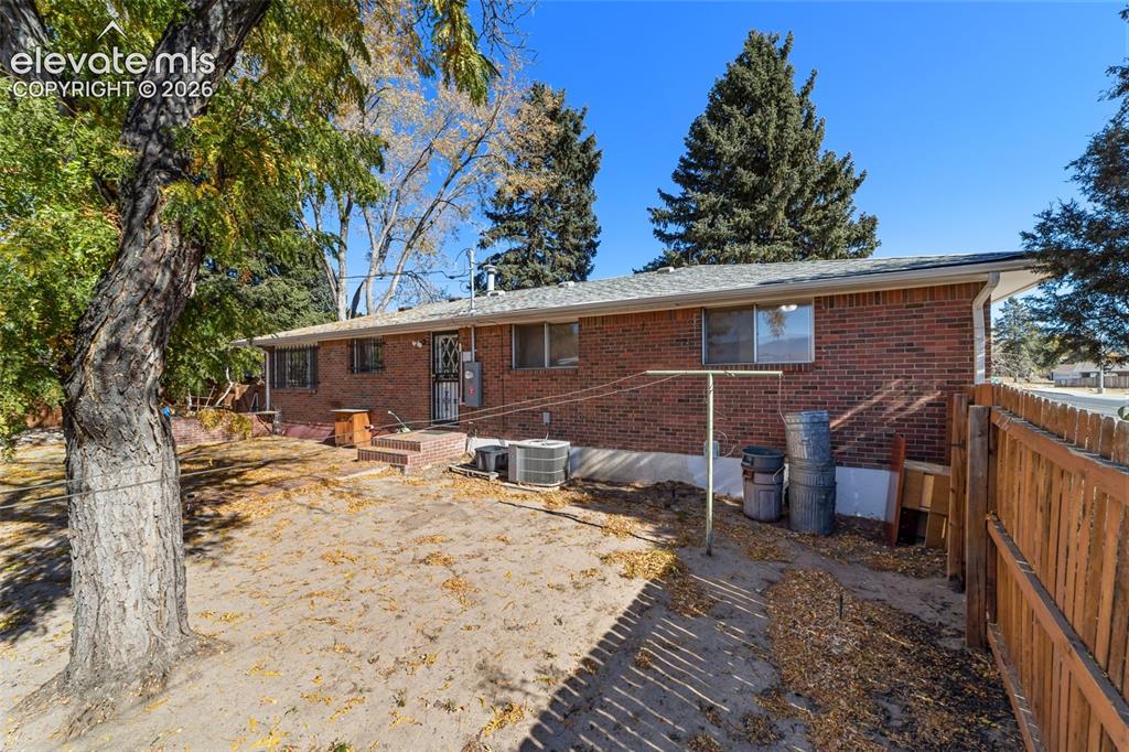 Image 41 of 50: Rear brick exterior featuring multiple windows and a private fenced yard