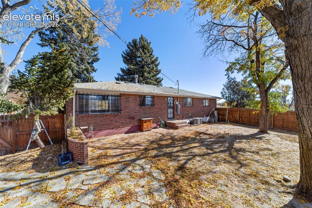 Image 43 of 50: Expansive backyard featuring a red brick exterior, mature trees, a wood pri