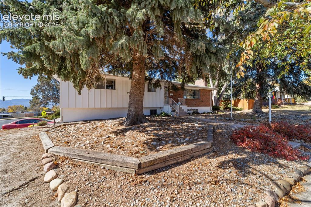 Image 48 of 50: Split-level residence featuring a brick and vertical siding exterior, matur