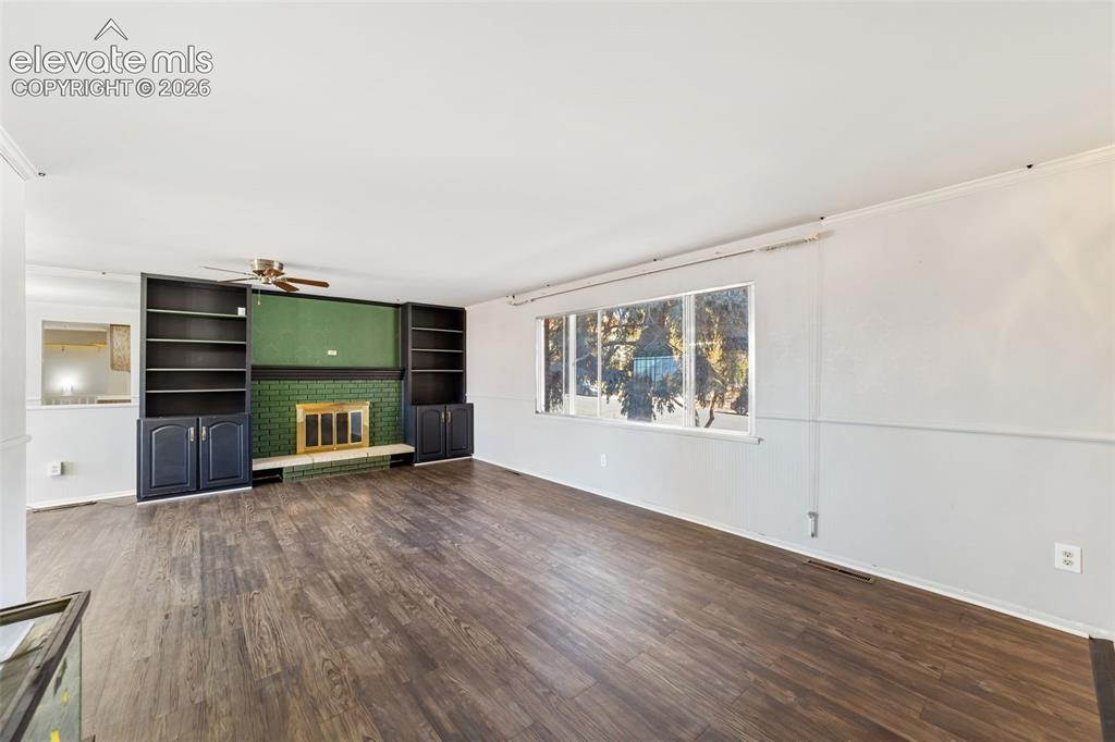 Image 7 of 50: Living area featuring wood-finish flooring, a fireplace with a green tile s