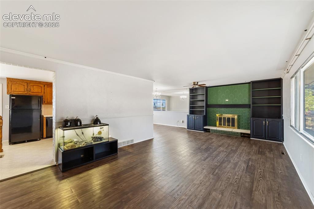 Image 8 of 50: Spacious living area featuring wood-finish flooring, a prominent fireplace