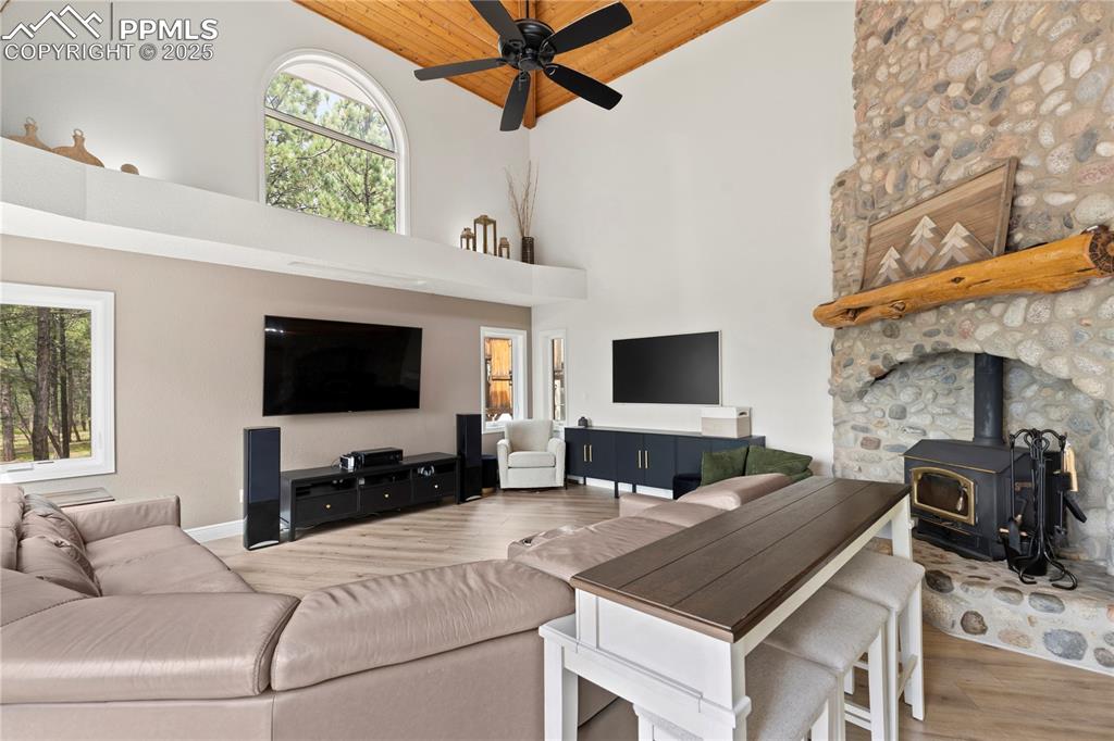 Image 12 of 47: The living room features vaulted ceilings, a fireplace, ceiling fans and lu