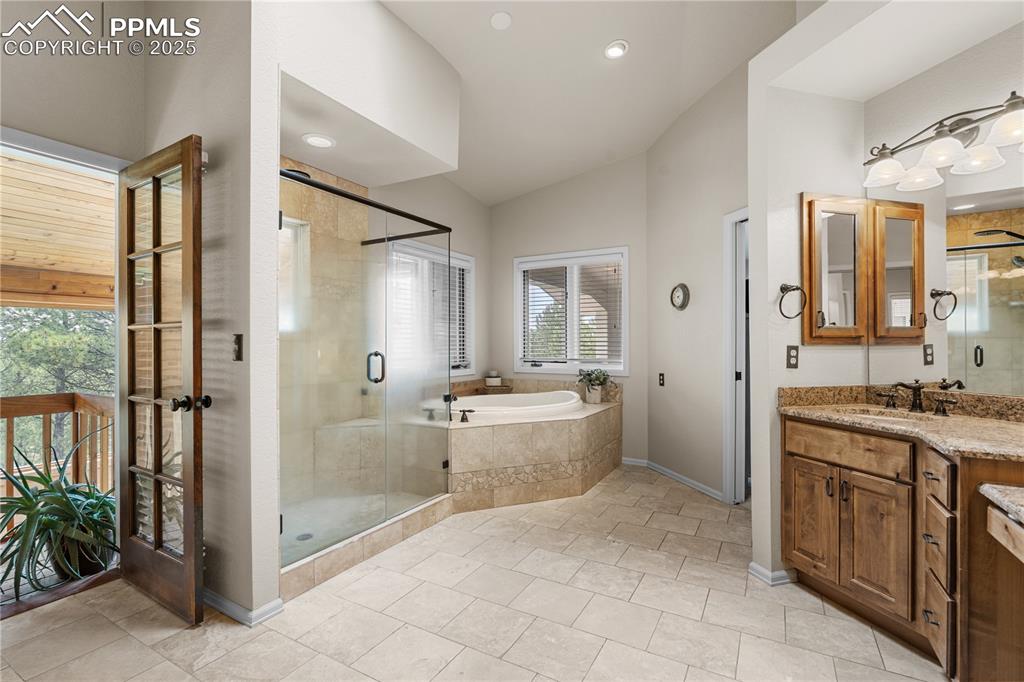 Image 29 of 47: The primary en-suite overlooks the sunroom, with a large soaking tub, dual 