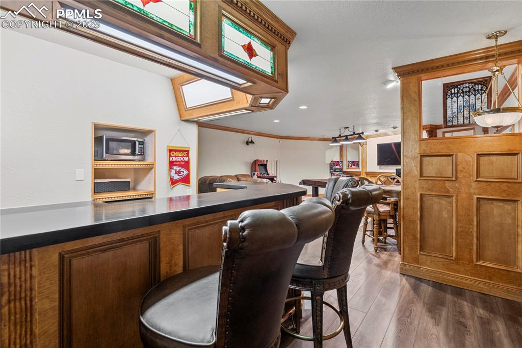 Image 34 of 47: Basement bar area with custom woodwork and stone counters