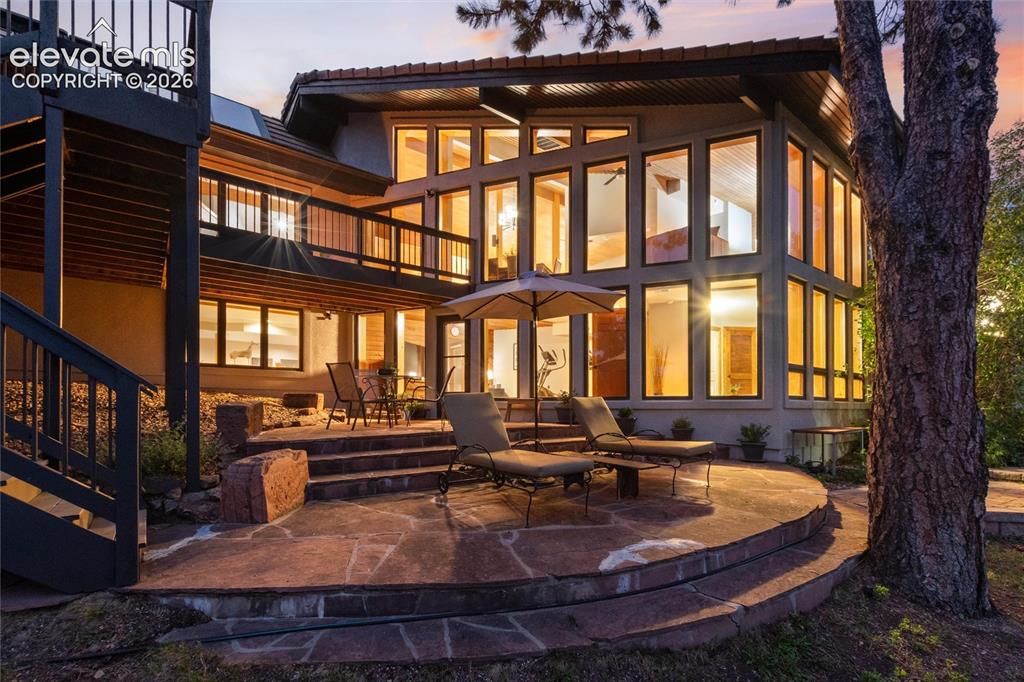 Caption: Multi-level residence featuring extensive floor-to-ceiling windows, a spacious flagstone patio, and 