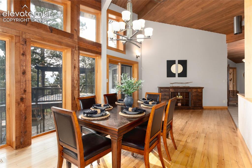 Image 11 of 50: Dining area featuring natural wood-finish flooring and a wood-paneled vault