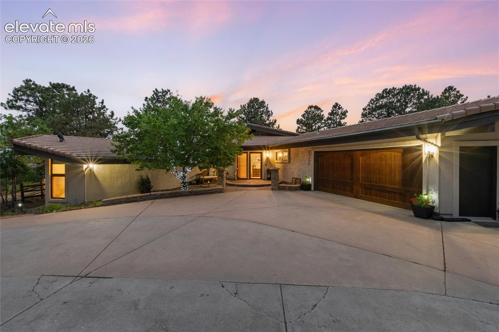 Image 2 of 50: Contemporary ranch-style residence featuring a prominent two-car wood-panel
