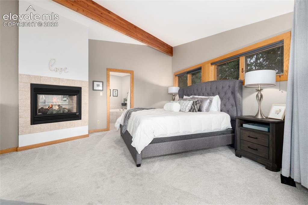 Image 20 of 50: Room featuring a gas fireplace with a tiled surround, exposed wood beams, a